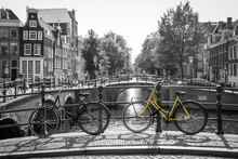 A Picture Of A Lonely Yellow Bike On The Bridge Over The Channel In Amsterdam. The Background Is Black And White.