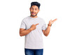 © Krakenimages.com - Handsome latin american young man wearing casual tshirt amazed and smiling to the camera while presenting with hand and pointing with finger.