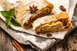 classic Viennese Christmas strudel with apples, mint and raisins. on a wooden cutting board with star anise, cinnamon sticks, top view