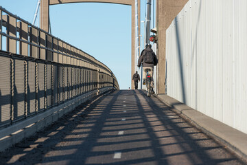 Wall Mural - People crossing a suspension bridge by foot and bicycle..