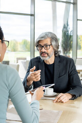 Wall Mural - Confident mature businessman in formalwear answering question of his colleague