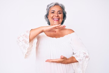 Wall Mural - Senior hispanic grey- haired woman wearing casual clothes gesturing with hands showing big and large size sign, measure symbol. smiling looking at the camera. measuring concept.