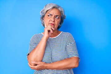 Wall Mural - Senior hispanic grey- haired woman wearing casual clothes serious face thinking about question with hand on chin, thoughtful about confusing idea