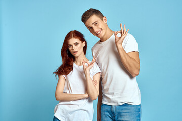 enamored man and woman in jeans and a T-shirt on a blue background hug each other and have fun