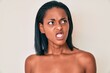Young african american woman standing topless showing skin angry and mad screaming frustrated and furious, shouting with anger. rage and aggressive concept.