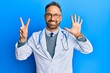 © Krakenimages.com - Handsome middle age man wearing doctor uniform and stethoscope showing and pointing up with fingers number seven while smiling confident and happy.