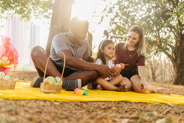 Wall Mural - Latin family celebrating Easter. curly girl wearing bunny ears and painting an easter egg