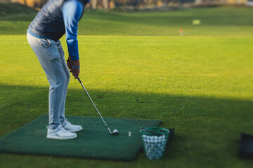 Group of golfers practicing and training golf swing on driving range practice, men playing on golf course, golf ball at golfing complex club resort