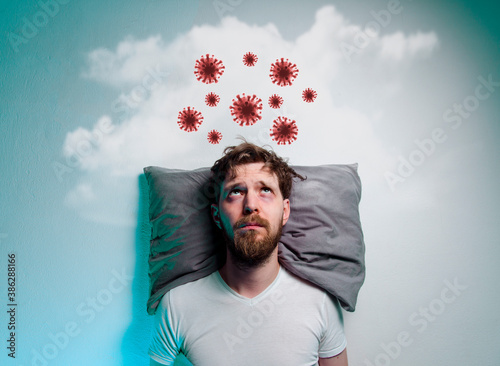 Coronavirus, covid-19 phobia, fear of pandemics. Man laying in bad and thinking about danger of a virus