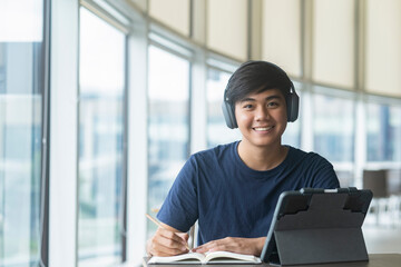 Young collage student using computer and mobile device studying online.