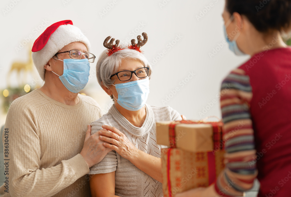 People with gifts wearing facemasks on Christmas. - obrazy, fototapety, plakaty 