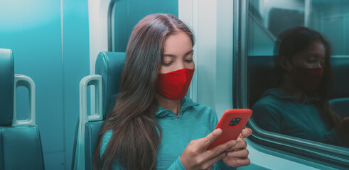 Face mask in public transport like train, bus. Woman passenger using mobile phone with face covering on subway commute ride at night.