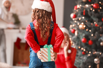 Cute girl hiding gift for her parents on Christmas eve