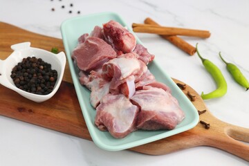 Fresh raw goat meat or mutton or lamb pieces. Preparation for Indian mutton curry. Spice at the background such as cinnamon sticks, red chili powder, black pepper & coriander. Copy space.