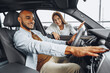© fotofabrika - Young attractive woman salesperson in car showroom showing a car to her male client