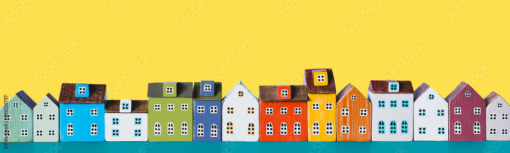 Row of wooden miniature colorful retro houses on a yellow background - obrazy, fototapety, plakaty 