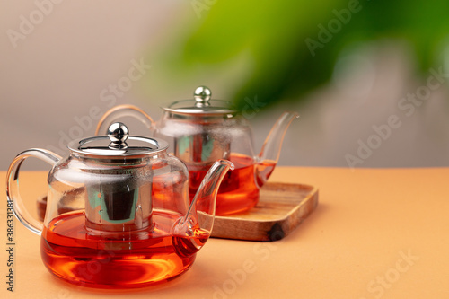 Fotografía Glass teapot with black tea on background of blurred foliage