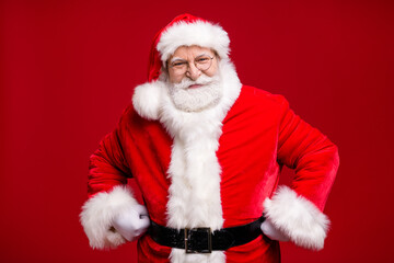 Wall Mural - Photo of retired old man grey beard fists hips self-assured attend educate naughty kid play strict grandpa wear santa costume belt coat spectacles headwear isolated red color background