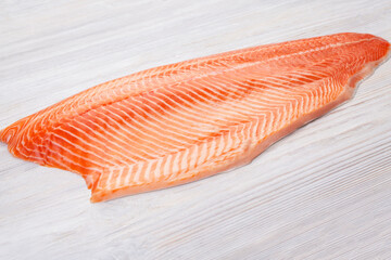 Half raw salmon fillet on wooden table