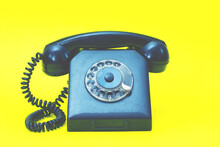 A Vintage Landline Telephone In Blue And Yellow Colors. A Retro Style Dial Phone On Yellow Background.