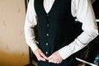 © Serhii - Man fastens the buttons on man's vest. The groom in shirt standing in room. Close up.