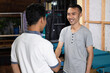 © Odua Images - smiling Asian male owner shaking hands when meeting customers at the screen printing office