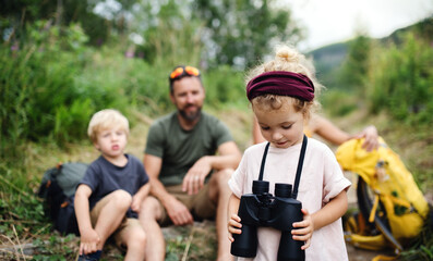 Wall Mural - family with small children hiking outdoors in summer nature, sitting and resting.