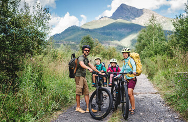 Wall Mural - family with small children cycling outdoors in summer nature.