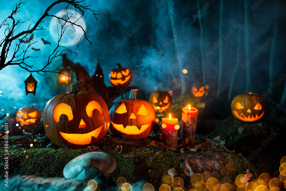 Halloween pumpkins on dark spooky forest with blue fog in background. - obrazy, fototapety, plakaty 