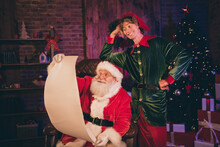 Photo Portrait Of Santa Claus And Elf Reading Nice And Naughty List Together
