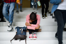 Depressed Young Student With Face Mask Sitting On Floor Back At College Or University, Coronavirus Concept.
