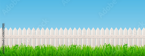 Fotomural White wooden picket fence and green grass on background of blue sky
