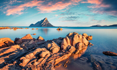 Unbelievable sunset with Tavolara mountain on background. Wonderful summer seascape of Mediterranean Sea, Porto Taverna beach, Sardinia island, Italy, Europe. Beauty of nature concept background.