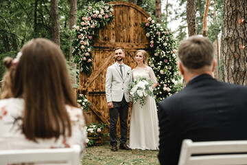 wedding day of the bride and groom,the groom and the bride stand near the wedding decorations where the wedding ceremony takes place,holiday of a young family