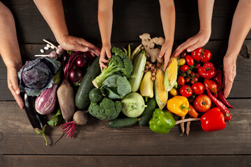 Wall Mural - Heap of fresh ripe vegetables on a wooden background with hands. Harvest from the home garden.