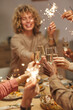 © Seventyfour - Vertical close up of people toasting with champagne glasses while enjoying dinner party with friends and family and holding sparklers