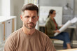 © Seventyfour - Portrait of mature bearded architect looking camera and smiling while sitting at drawing desk in sunlight, copy space
