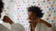 © nimito - Afro man brushing teeth with toothbrush standing near mirror in bathroom