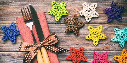 Sticker - Top view of holiday set of fork and knife on wooden background. Close up of Christmas decorations and toys. New Year Eve concept