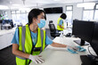 © WavebreakMediaMicro - Woman wearing hi vis vest and face mask cleaning the office using disinfectant