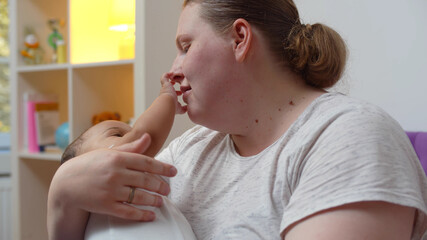 Wall Mural - Overweight caucasian mother rocking adopted mixed race infant at home