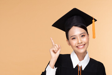 Beautiful Attractive Asian woman graduated in cap and gown smile so proud and happiness,Isolated on Beige background,Education Success Concept