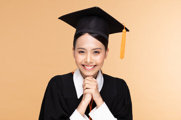 Beautiful Attractive Asian woman graduated in cap and gown smile so proud and happiness,Isolated on Beige background,Education Success Concept