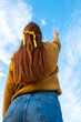 red-haired girl in a sweater reaches for the sky