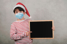 Merry Christmas,funny Kid With Medical Mask Holding A Blackboard