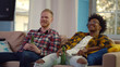 © nimito - Cheerful multiethnic male friends with beer watching tv at home