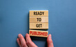 © Dzmitry - Male hand placing a block with word 'published' on a blocks tower with words 'ready to get published'. Beautiful blue background. Copy space.