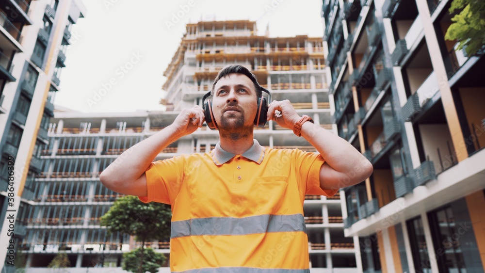 Builder covers his ears, ear muff to protect workers ears. Construction ...