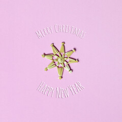 Christmas card with Christmas straw snowflake on pink background and Christmas greeting