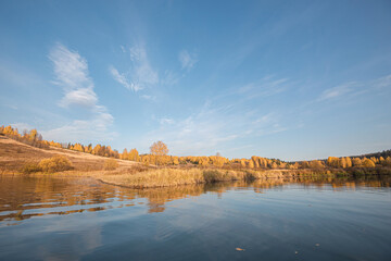 Wall Mural - panoramic autumn landscape of the river valley yellow, golden leaves and grass, sun rays.
